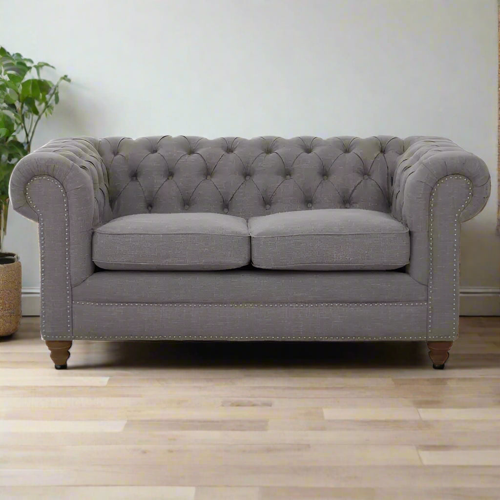 Introducing our classic chesterfield two-seat sofa, featuring a button-tufted back that exudes luxury with a touch of warmth. Timeless and elegant, it boasts gently scrolled arms that complement its smooth lines. The nail head trims add a finishing touch to the design, making this sofa a sophisticated addition to any living space.