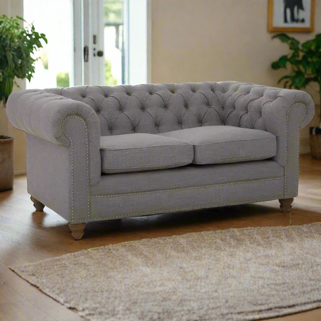 Introducing our classic chesterfield two-seat sofa, featuring a button-tufted back that exudes luxury with a touch of warmth. Timeless and elegant, it boasts gently scrolled arms that complement its smooth lines. The nail head trims add a finishing touch to the design, making this sofa a sophisticated addition to any living space.