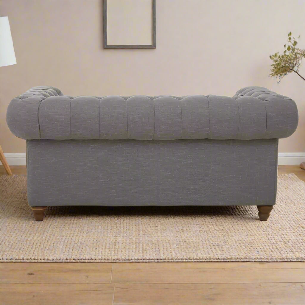 Introducing our classic chesterfield two-seat sofa, featuring a button-tufted back that exudes luxury with a touch of warmth. Timeless and elegant, it boasts gently scrolled arms that complement its smooth lines. The nail head trims add a finishing touch to the design, making this sofa a sophisticated addition to any living space.
