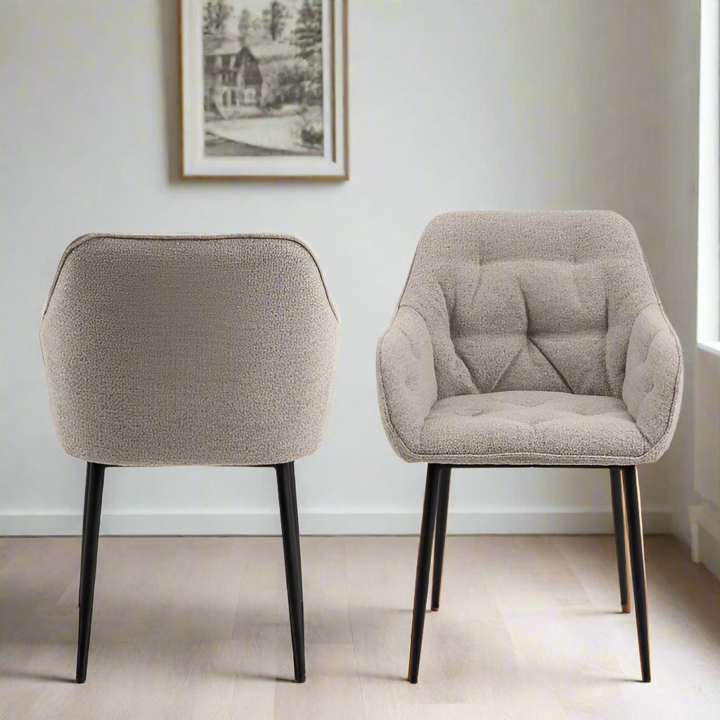 "Beige dining chair with armrests, soft bouclé fabric, tufting detail, and black powder-coated steel legs, perfect for modern dining spaces."