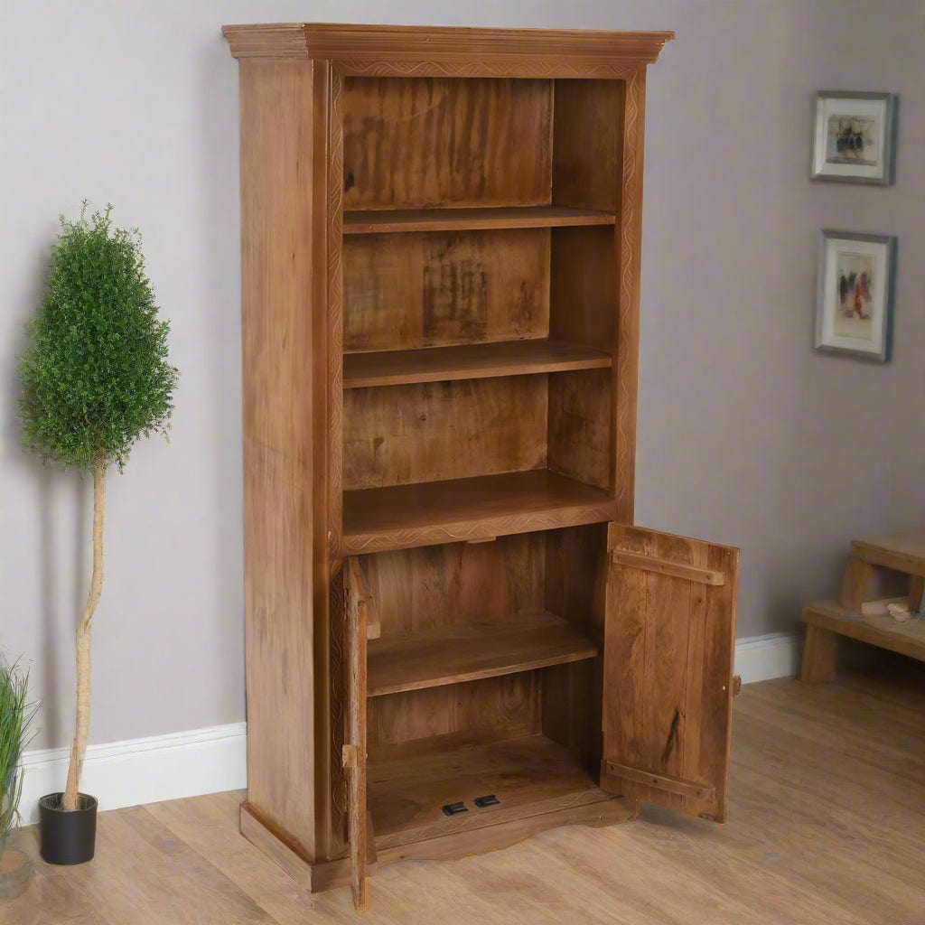 Handcrafted large bookcase made from eco-sourced mango wood, featuring hand-carved detailing, open shelving, and a two-door cupboard with a light whitewash finish