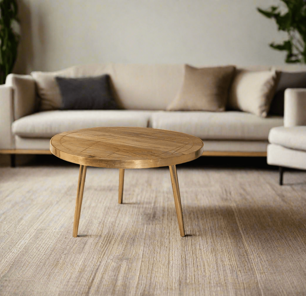 Round coffee table with gold metal inlays on the solid mango wood top, gold metal frame around the edge, and three angled metal legs, in a light natural finish.