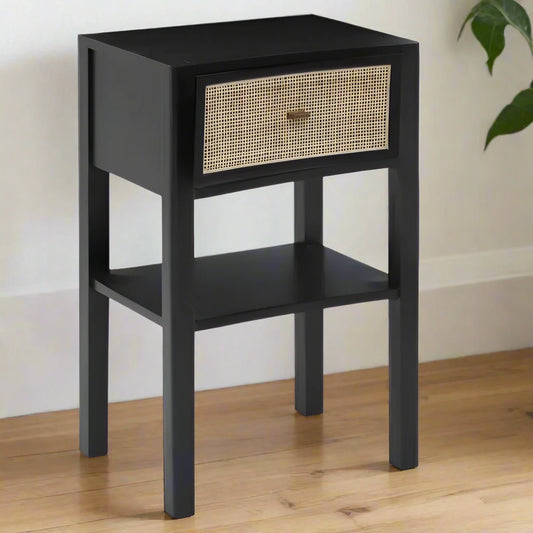 A stylish black rattan bedside table with one drawer, featuring a modern design that blends sleek black wood and intricate rattan detailing. This bedside table offers both functionality and charm, providing storage for essentials while adding a touch of texture to your bedroom decor. The spacious drawer is perfect for keeping items organized and out of sight. Ideal for contemporary or boho-inspired interiors, this black rattan bedside table enhances your bedroom with style and practicality.