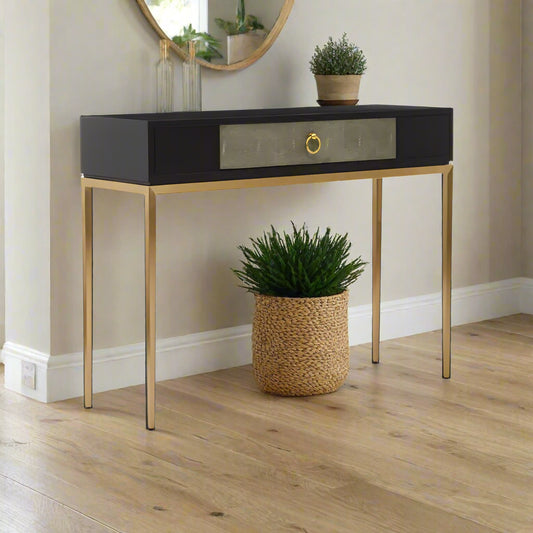 Elegant Derude console table with a grey shagreen-effect drawer, solid black wood top, and modern gold-finish metal legs. Combines stylish storage and luxury, perfect for hallways, living rooms, or bedrooms.