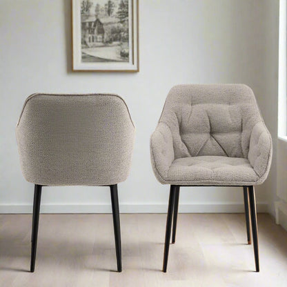 "Beige dining chair with armrests, soft bouclé fabric, tufting detail, and black powder-coated steel legs, perfect for modern dining spaces."