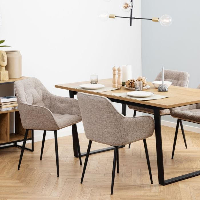 Beige dining chair with armrests, soft bouclé fabric, tufting detail, and black powder-coated steel legs, perfect for modern dining spaces.