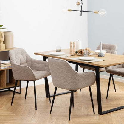 Beige dining chair with armrests, soft bouclé fabric, tufting detail, and black powder-coated steel legs, perfect for modern dining spaces.