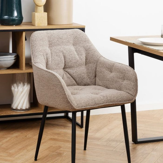Beige dining chair with armrests, soft bouclé fabric, tufting detail, and black powder-coated steel legs, perfect for modern dining spaces.