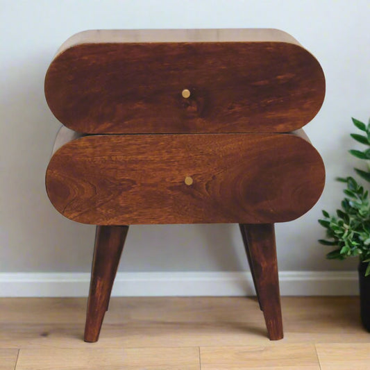 Quirky Capsule-Style Bedside Table with round drawer designs, crafted from 100% solid mango wood in a warm chestnut finish. Supported by Nordic-style legs and featuring shiny brass knobs for a modern, stylish look.