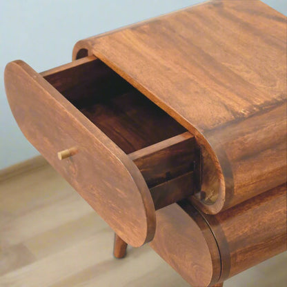 Quirky Capsule-Style Bedside Table with round drawer designs, crafted from 100% solid mango wood in a warm chestnut finish. Supported by Nordic-style legs and featuring shiny brass knobs for a modern, stylish look.