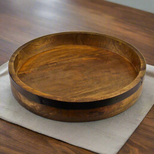 A Dark Wood Circular Serving Tray featuring a sleek, round design with a rich, dark wood finish. This elegant serving tray is perfect for serving drinks, appetizers, or organizing small items. The smooth, durable surface adds sophistication to any dining or living space, while the round shape enhances its stylish appeal. Ideal for both functional and decorative use, this dark wood tray complements modern, rustic, or traditional interiors, offering both practicality and charm to your home decor.