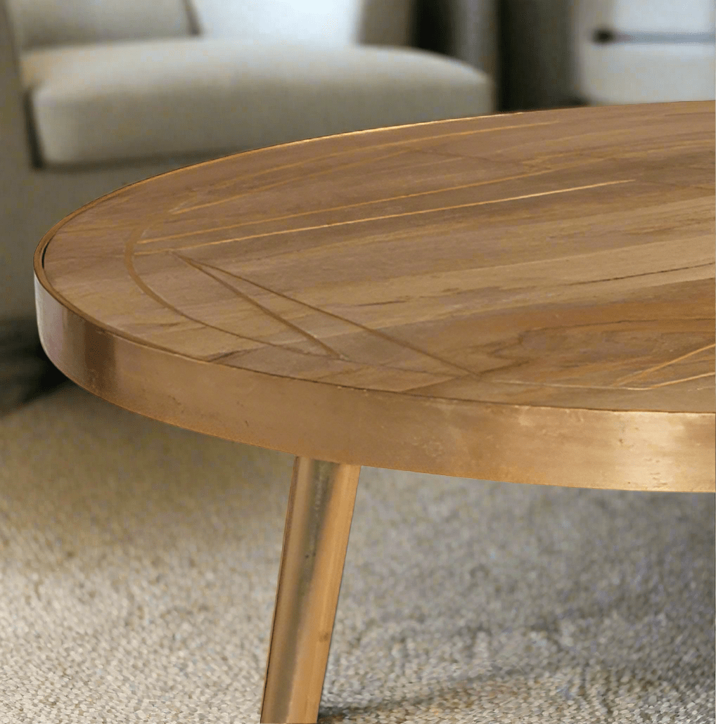 Round coffee table with gold metal inlays on the solid mango wood top, gold metal frame around the edge, and three angled metal legs, in a light natural finish.