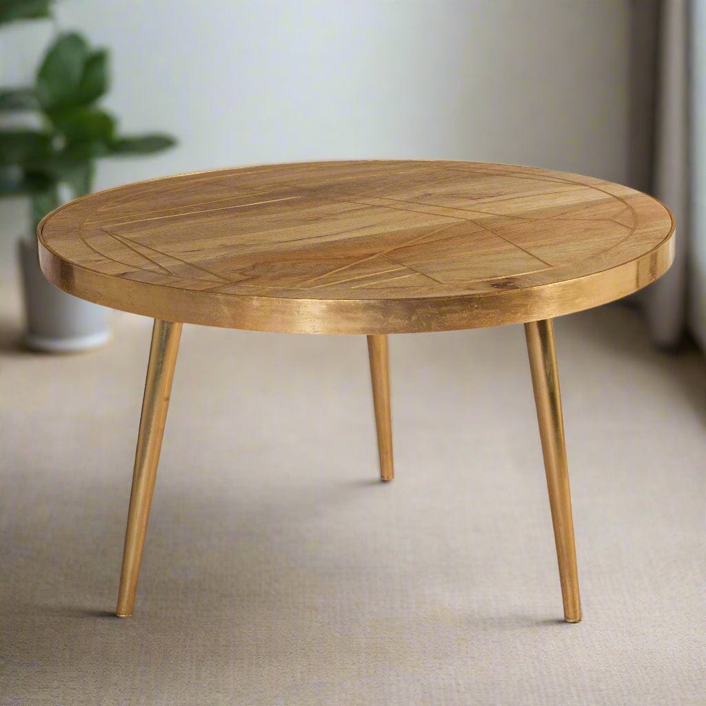 Round coffee table with gold metal inlays on the solid mango wood top, gold metal frame around the edge, and three angled metal legs, in a light natural finish.