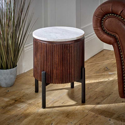 "Handcrafted bedside table with a natural marble top, fluted mango wood surround, and metal legs, perfect for holding drinks, remotes, and mobile phones, with easy maintenance."