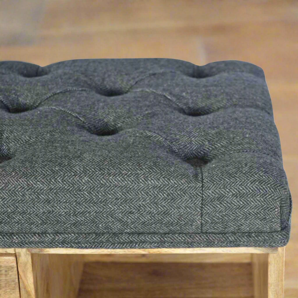 Small shoe storage bench with oak-ish finish, black tweed upholstered seat, 1 drawer with shiny knob, 6 open shelves, and 4 bun feet.