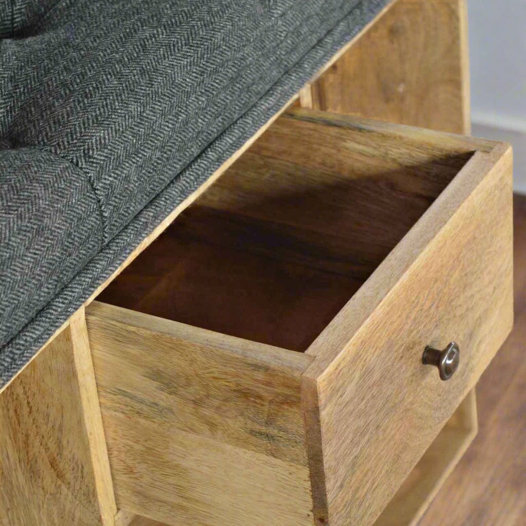 Small shoe storage bench with oak-ish finish, black tweed upholstered seat, 1 drawer with shiny knob, 6 open shelves, and 4 bun feet.