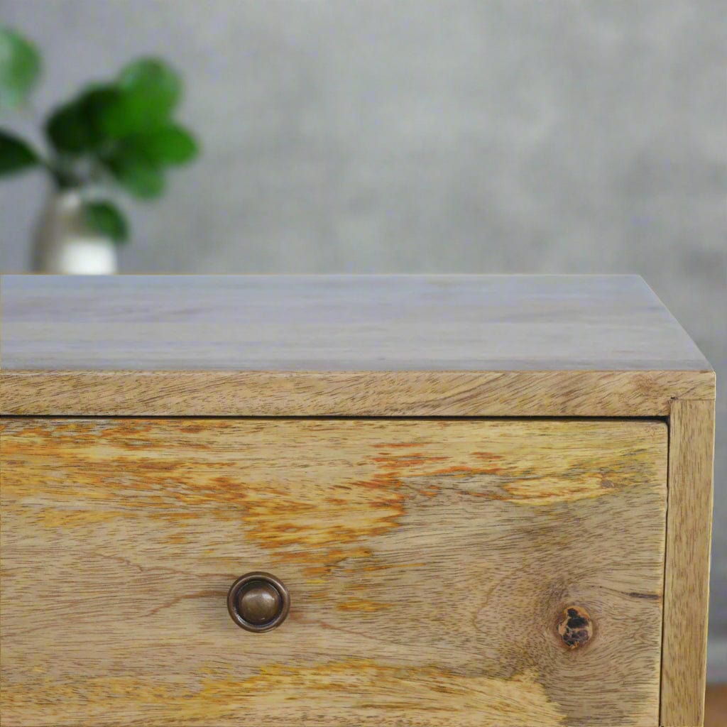 Nordi-inspired solid mango wood media unit with oak-like finish, four drawers, backless shelf for cable boxes, Scandinavian-style legs, and shiny knobs, perfect for modern living rooms.