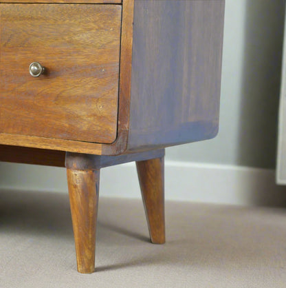 "Curved chest of drawers made from solid mango wood with chestnut finish, featuring shiny accent knobs, four Nordic-style legs, and smooth, rounded corners for a modern, contemporary look."