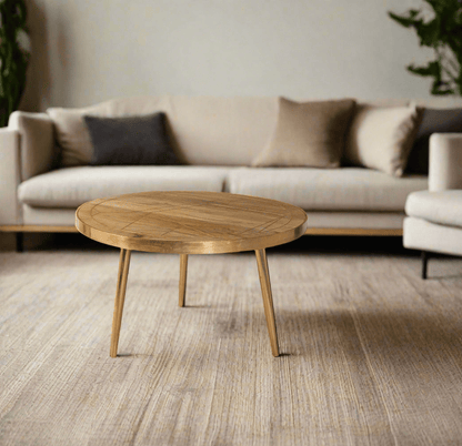Round coffee table with gold metal inlays on the solid mango wood top, gold metal frame around the edge, and three angled metal legs, in a light natural finish.