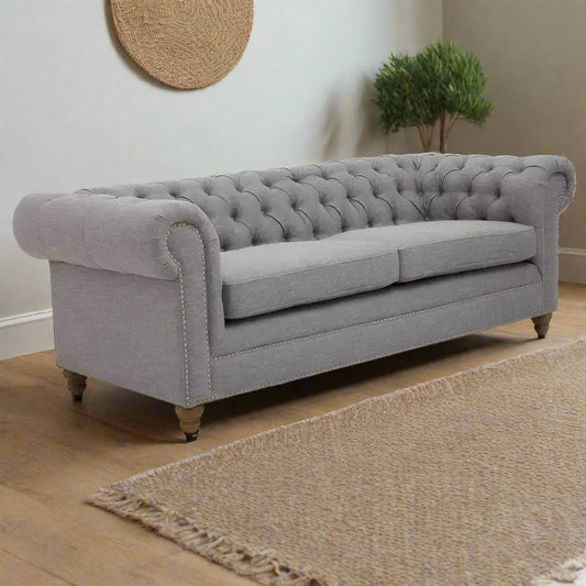 "Grey linen three-seat sofa with button tufted back, scrolled armrests, nailhead trims, sumptuous padding, and wooden feet for timeless elegance and comfort."